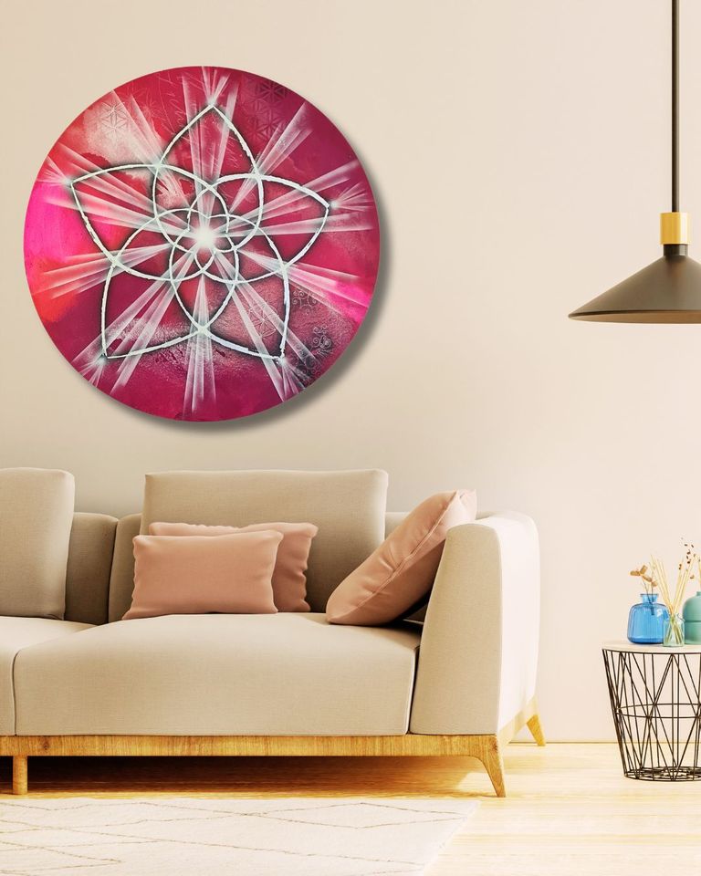 Runder, rosa-weißer Wandteppich mit einem stilisierten Blütenmuster hängt über einem hellen Sofa mit rosa Kissen in einem modernen Wohnzimmer.
